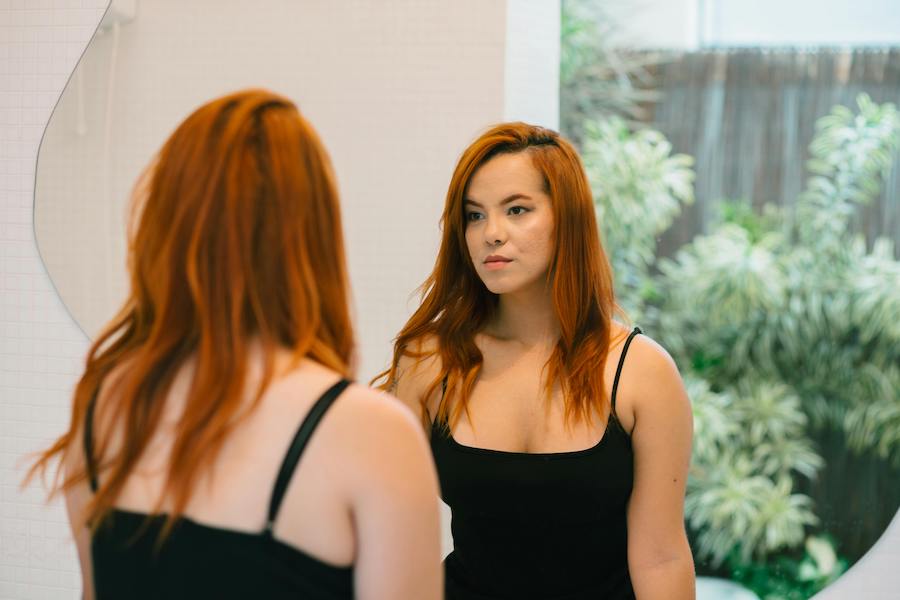Woman looking in mirror postpartum | The Peaceful Mind Counseling Center